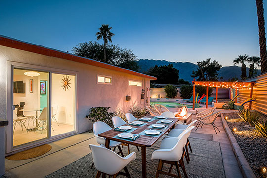 The Summit Palm Springs backyard dining with pool view at twilight.